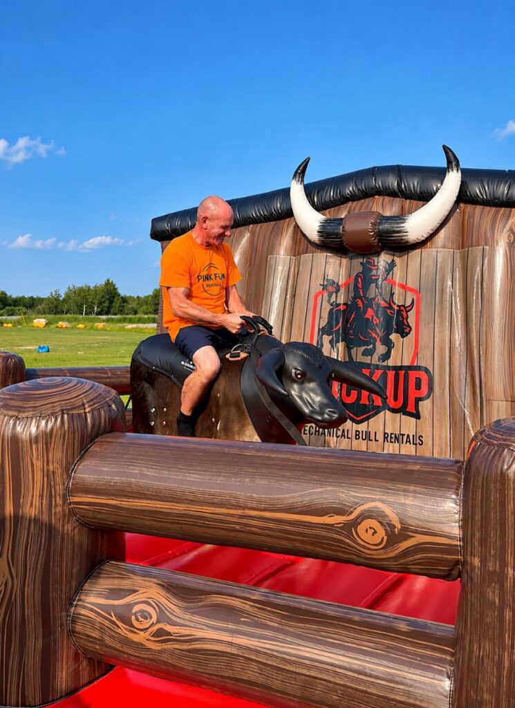 Pink Fun Rentals crew member riding the mechanical bull at an event